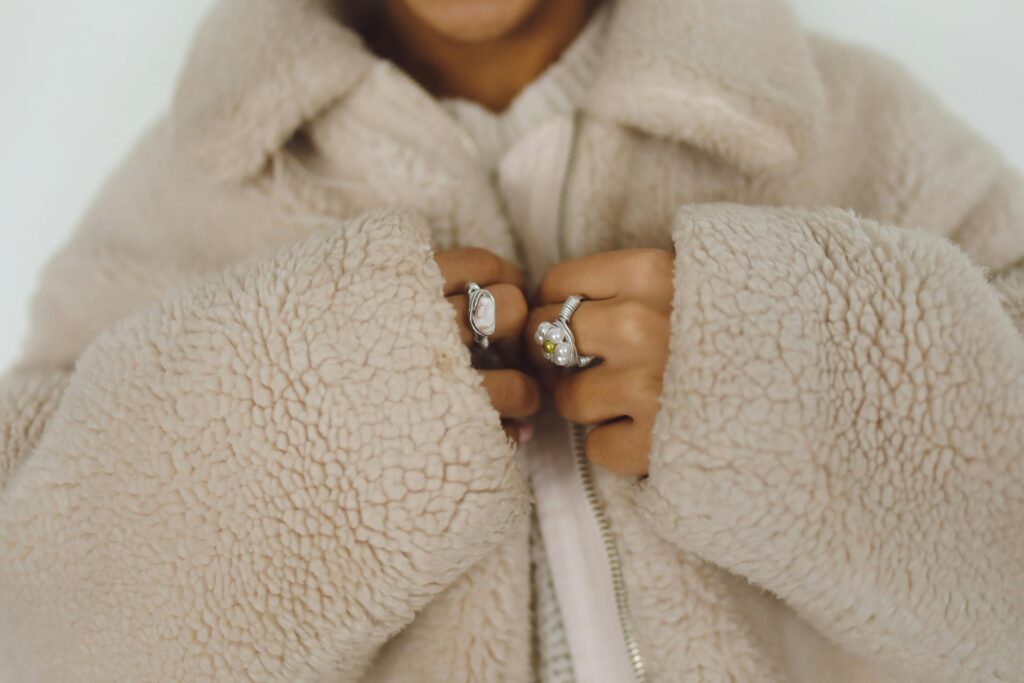 pexels-photo-6630904-6630904 Close-up of hands in a fluffy faux fur coat adorned with stylish rings.